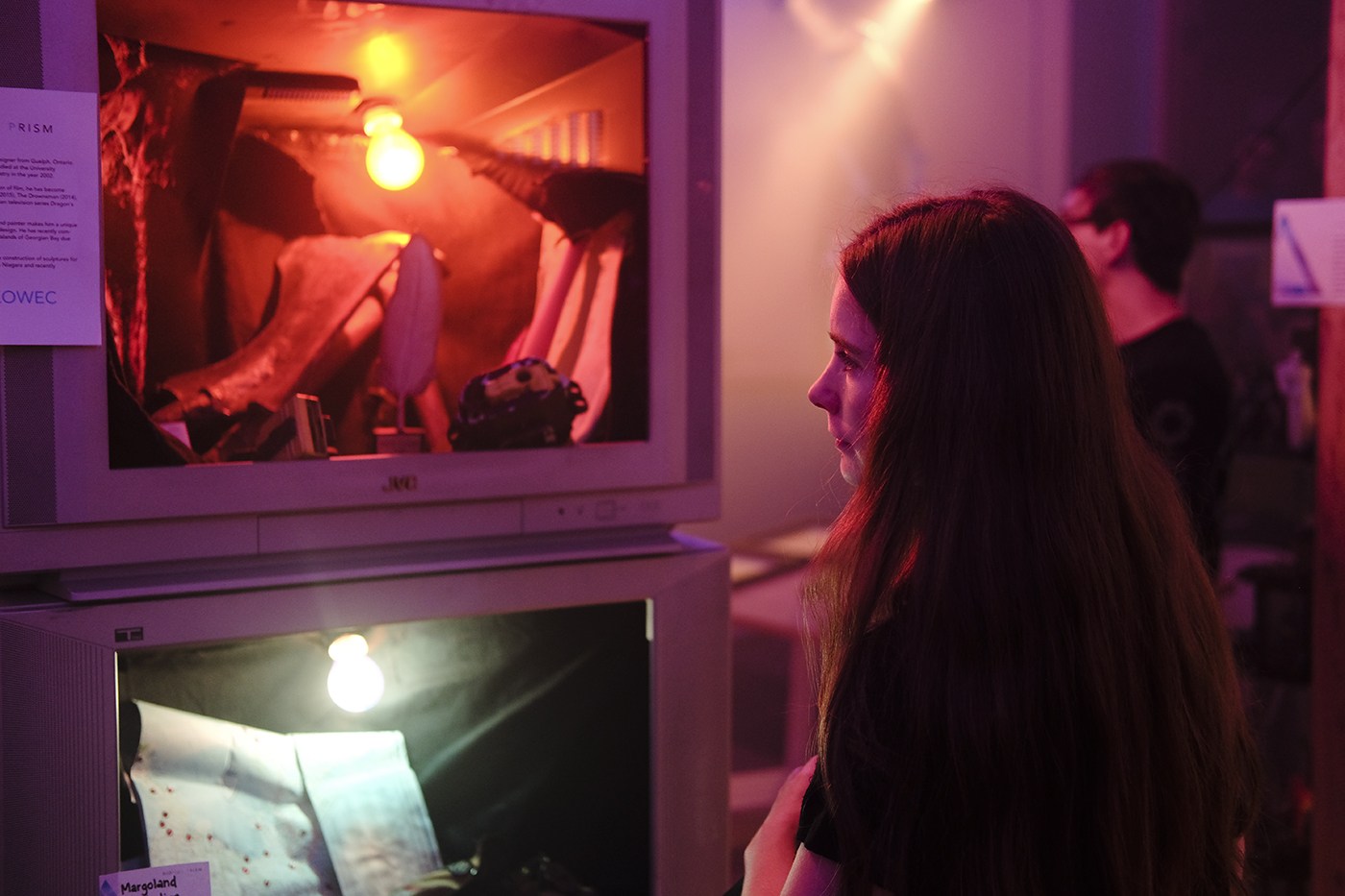 A visitor exploring a film installation built from televisions