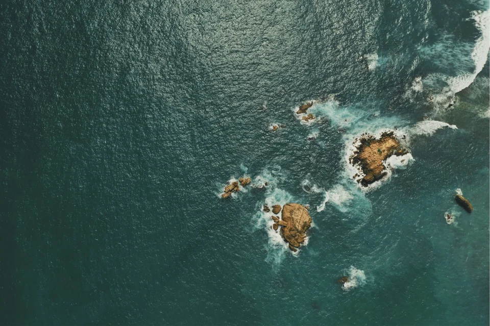 Aerial view of waves breaking around coastal rocks