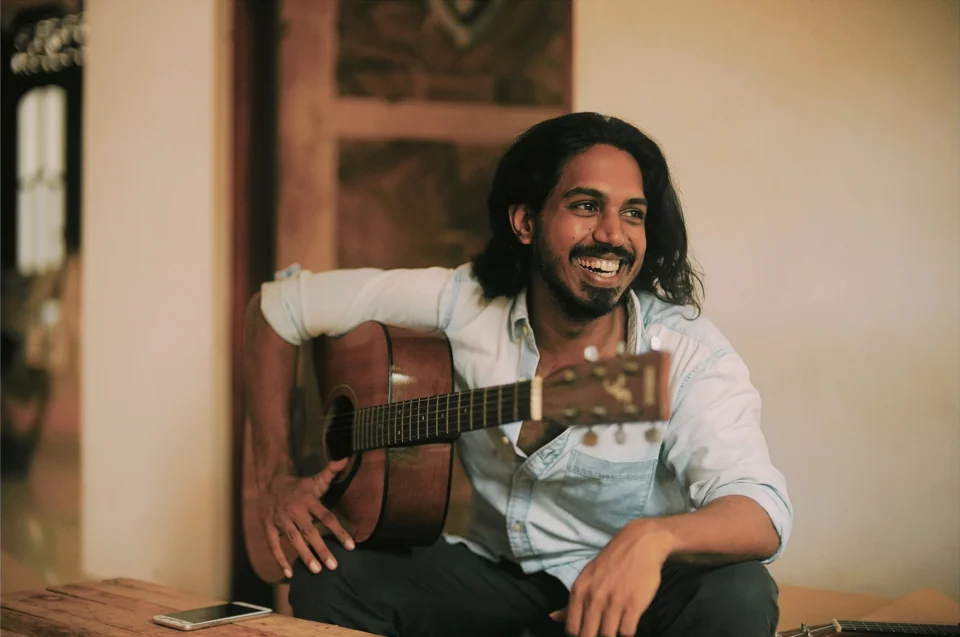 A seated musician smiling with a guitar