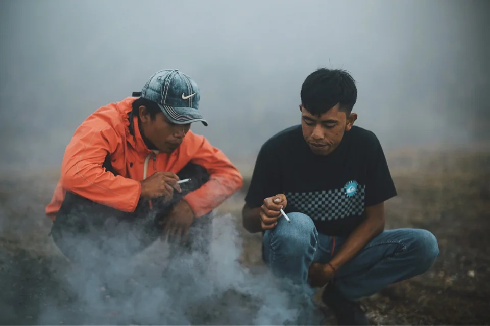 Two people seated beside steam on a mountain