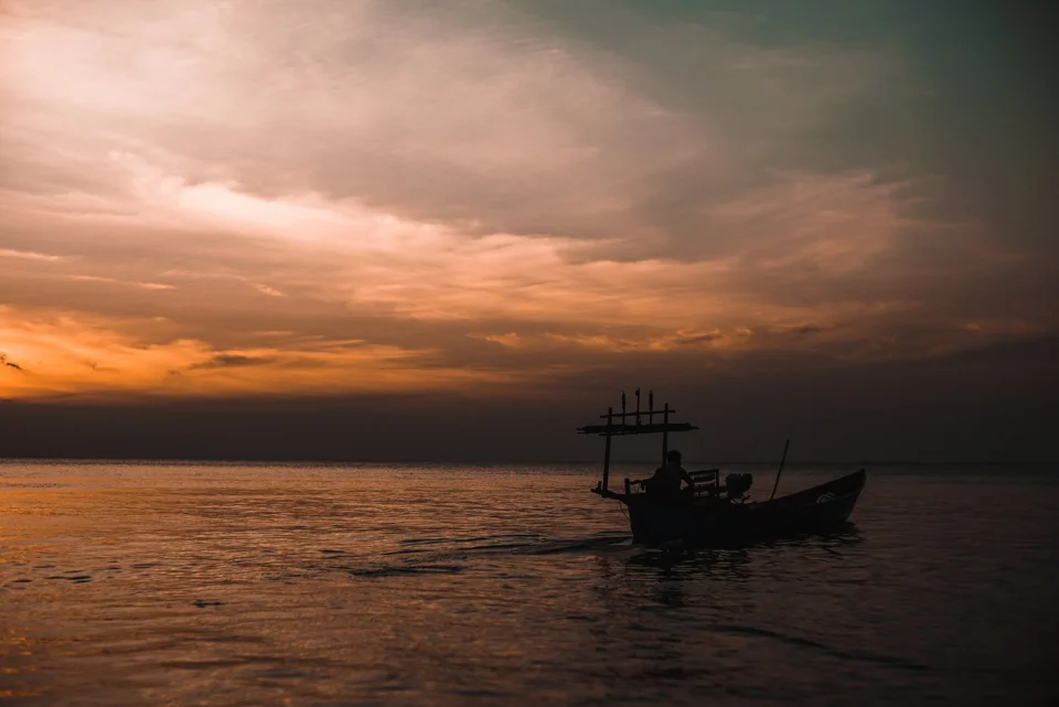 A fishing boat silhouetted against a sunset