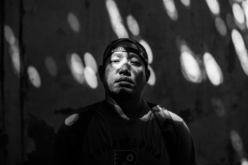 A black-and-white portrait beneath dappled light