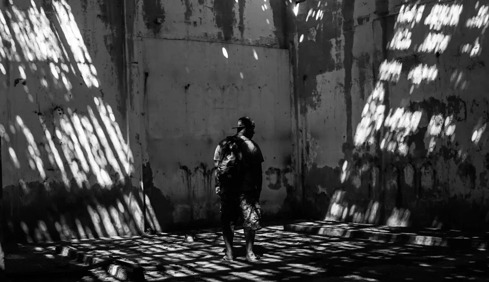 A figure standing in a patterned shaft of light