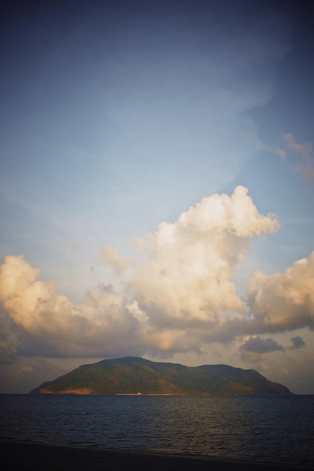 Sunlit clouds above a green island and blue water