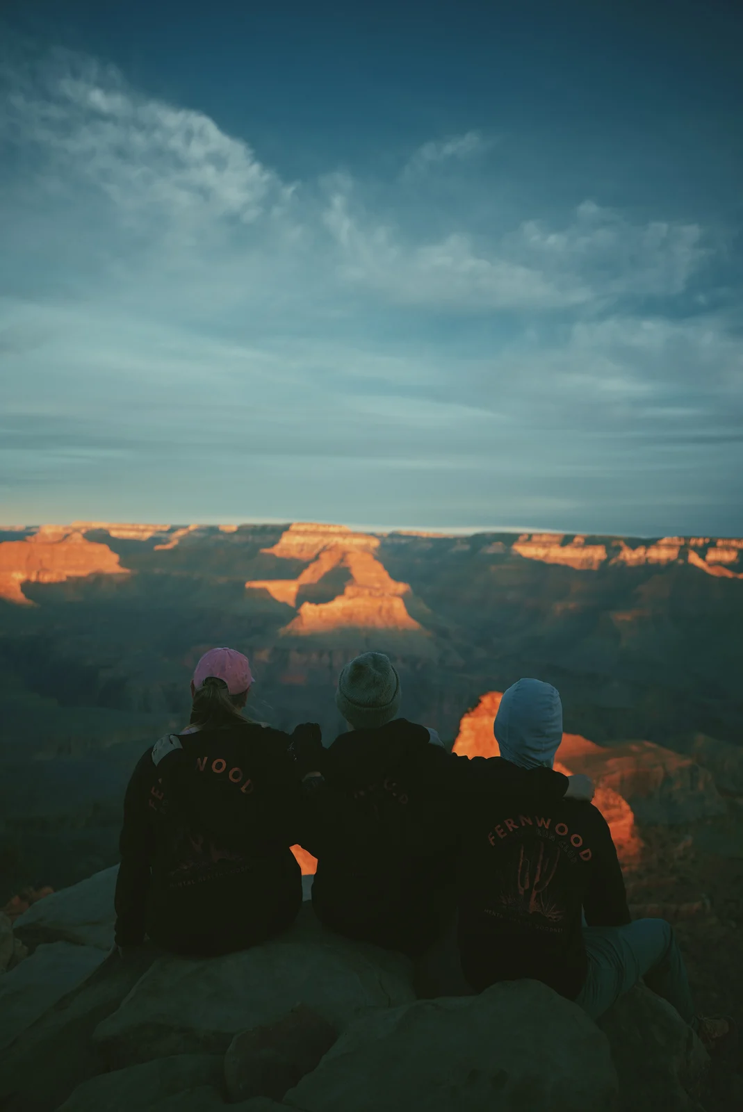 Three people watching the light across a canyon