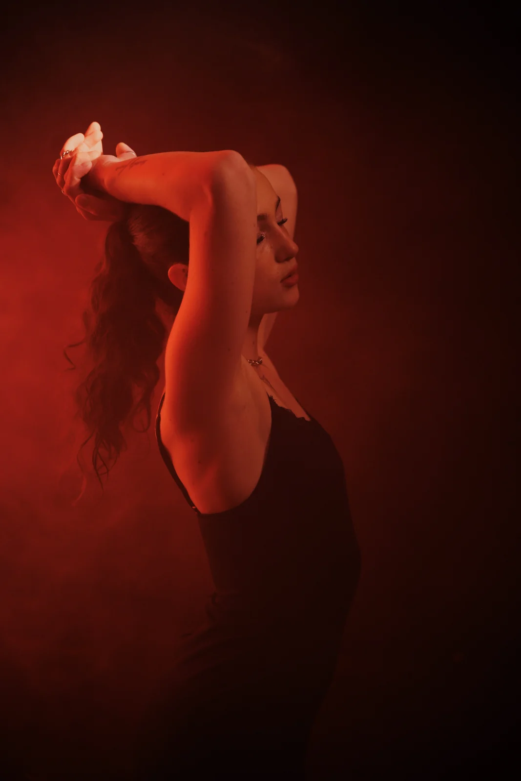 Portrait with raised arms in red light