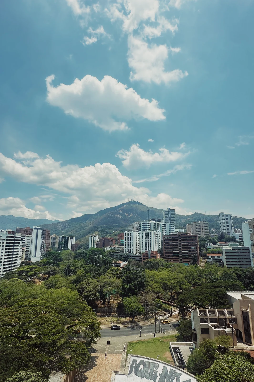 Clouds above a green city skyline and surrounding hills
