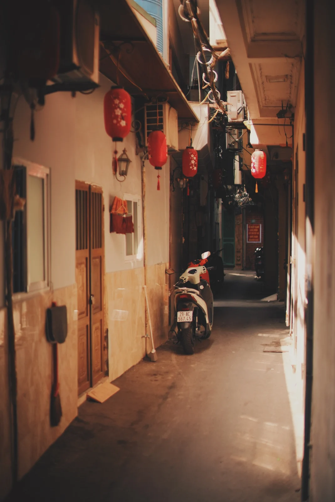 Lanterns and a scooter in a warm-toned alley