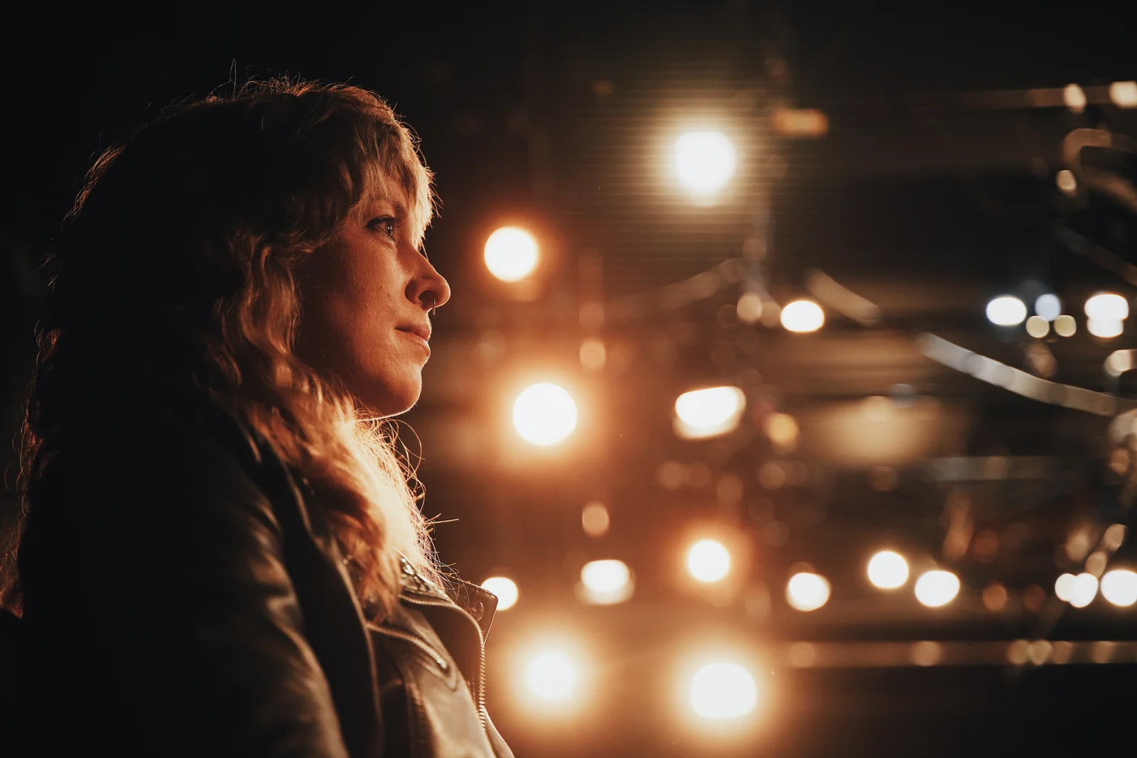 A woman in profile beneath warm glowing lights