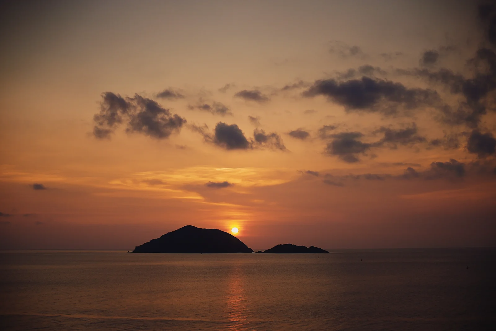 An orange sunset behind a coastal island