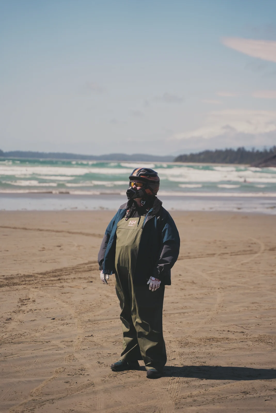 A helmeted person standing on a broad sandy beach