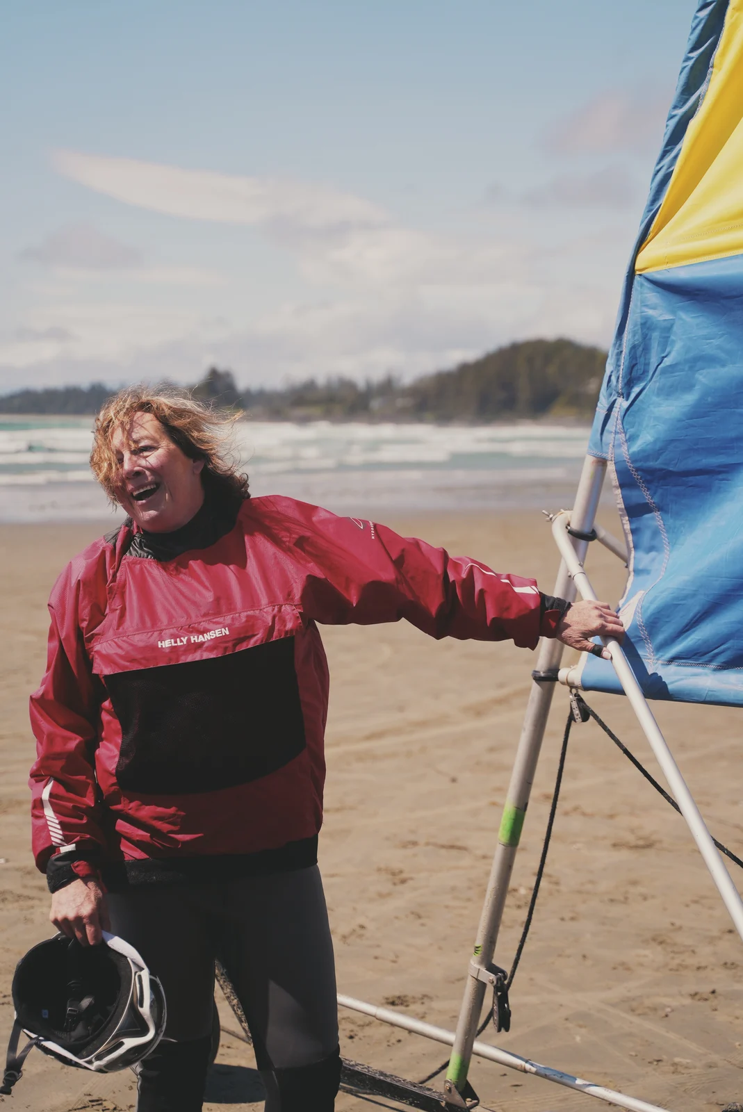 A laughing woman beside a sail on the beach