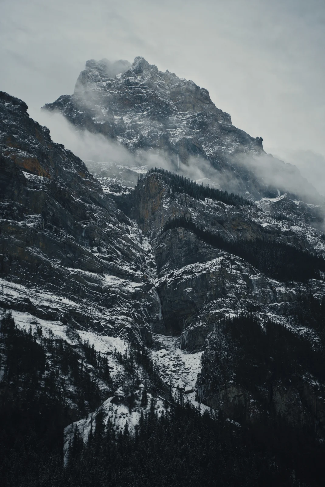 A jagged snowy mountain beneath low clouds