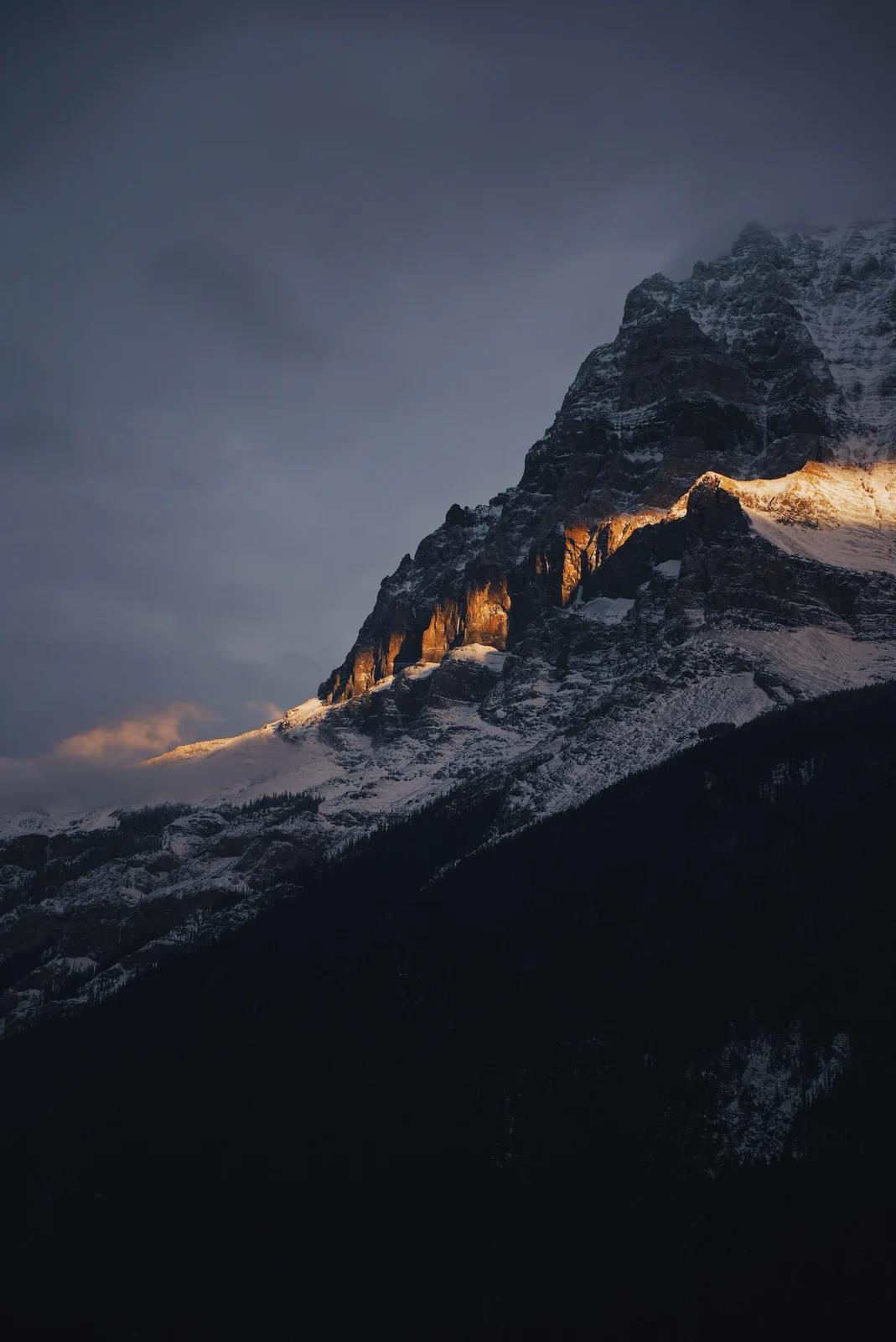 A stripe of orange sunlight across a snowy mountain