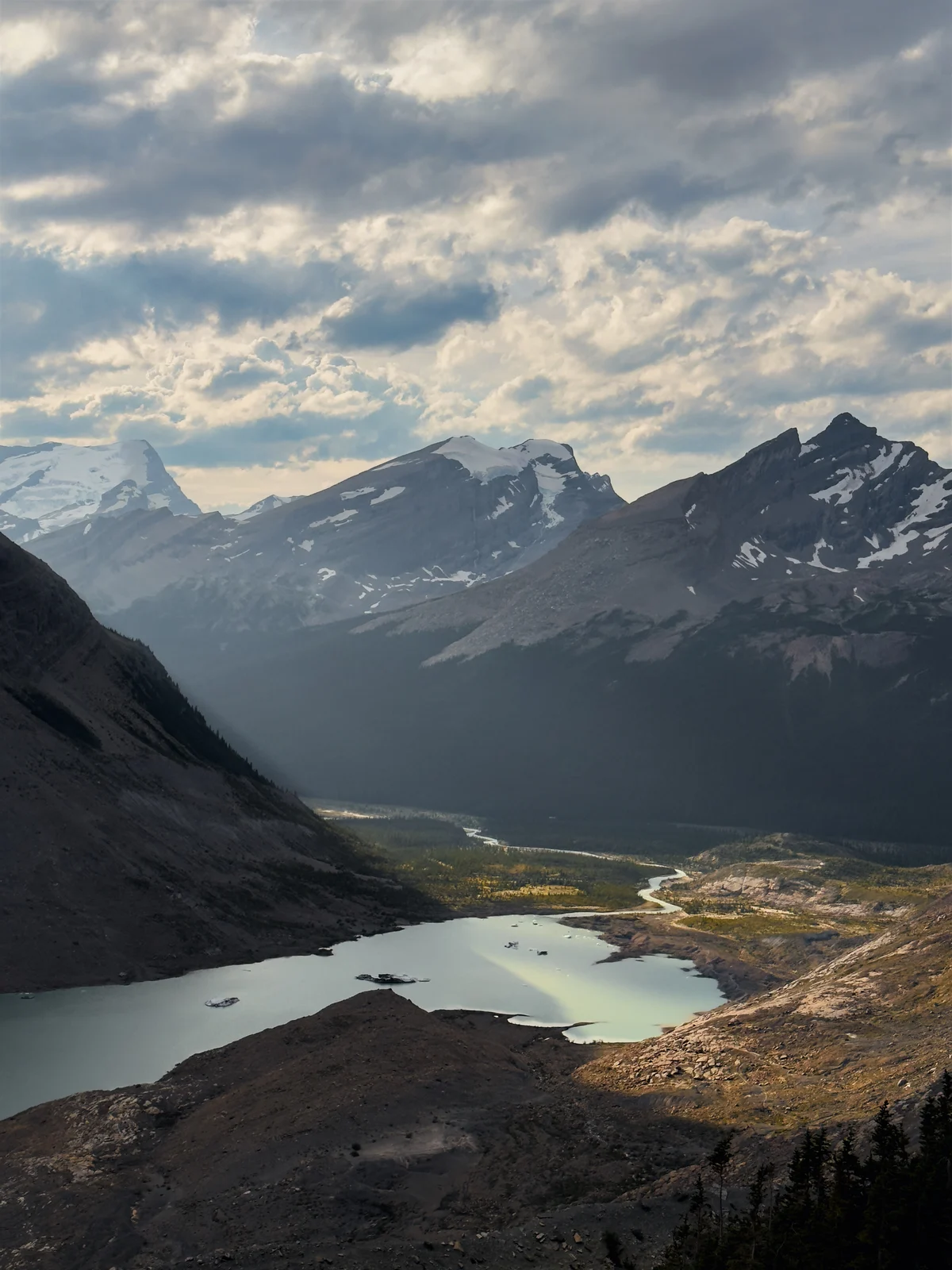 A mountain lake and distant valley beneath textured clouds