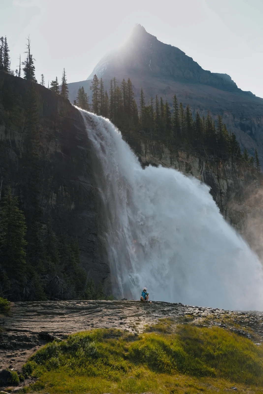 A tiny figure beside a powerful waterfall