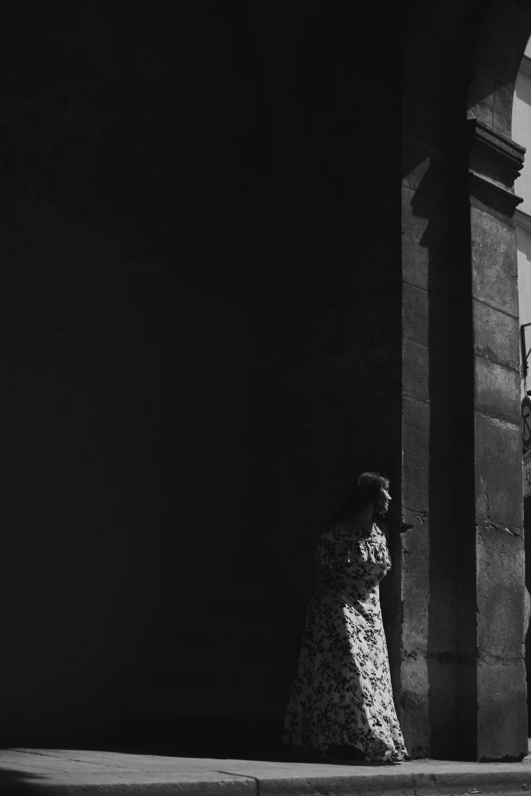 A woman standing at the edge of light in a deep doorway